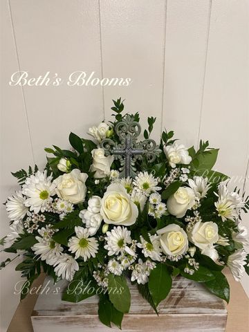 Elegant white floral arrangement with a decorative cross centerpiece.