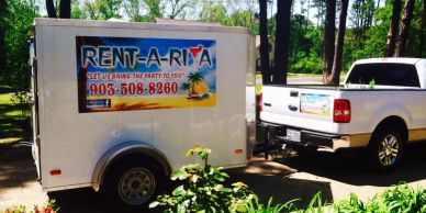 A white trailer and pickup truck with Rent-A-Rita party rental signage.