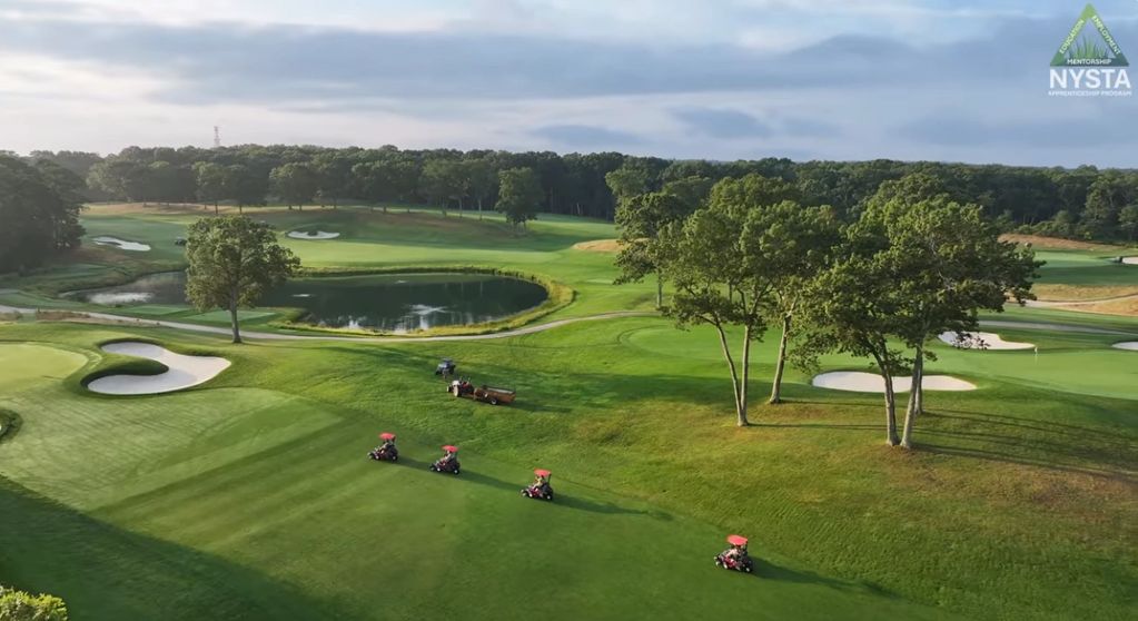 Golf course with four golf carts driving in a line.