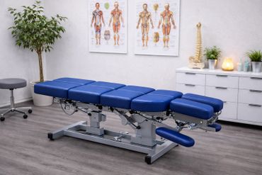 Blue adjustable chiropractic treatment table in a clinical room.
