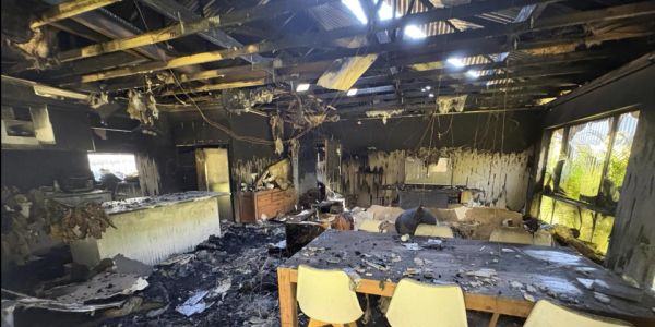 Interior of a fire-damaged room with charred furniture.