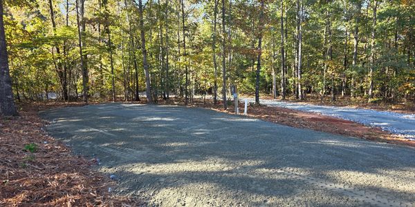 A cleared and leveled dirt area surrounded by trees in a forest setting.