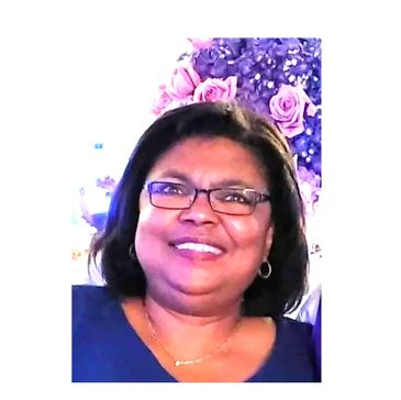 Smiling woman with glasses and floral background.