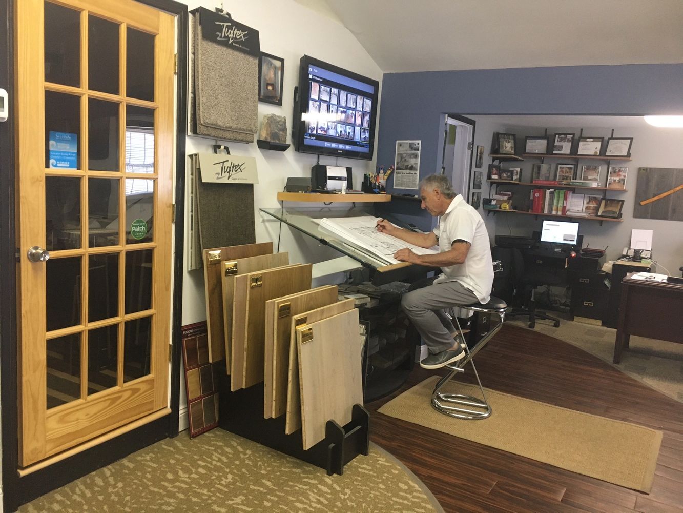 Frank Conzola working on a customer's flooring design at his drafting table in his office-showroom.