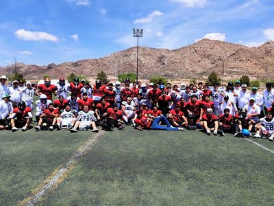 Equipos de fútbol americano posan juntos en campo abierto.