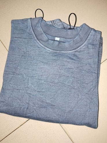 Folded gray sweater on tiled floor with black hangers.