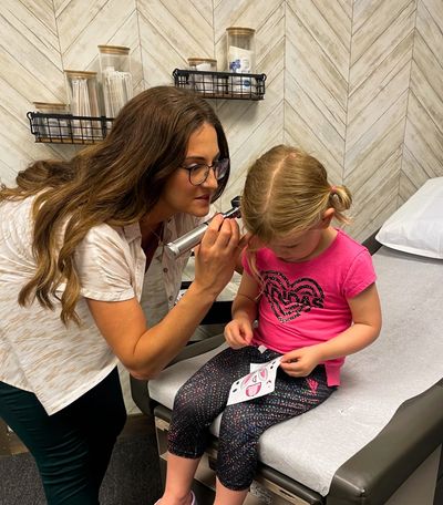 child having their ears examined on the exam table