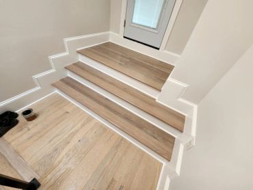 Wooden stairs with clean white trim and a door at the top.