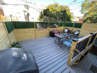 Cozy outdoor deck with seating, grill, and privacy fence adorned with greenery.