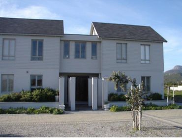 Two-story modern house with white exterior and a small tree in front.