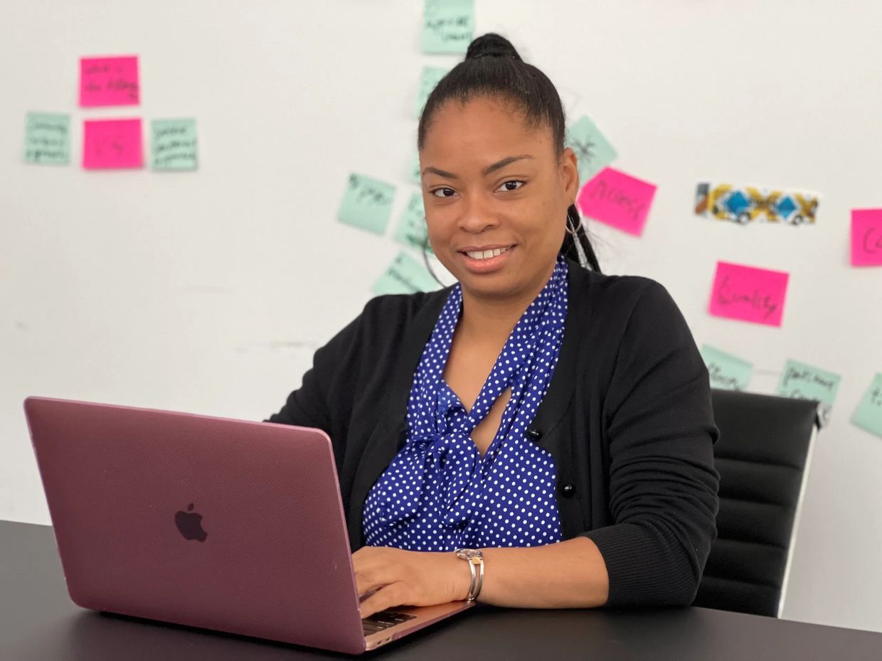 A picture of CEO Lishawn Alexander sitting at a desk with her computer open. 