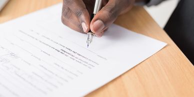 The hand of a person signing a contract.