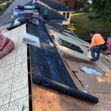 Workers installing roofing materials on a residential roof.