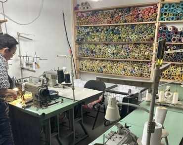 A tailor working with sewing machines and colorful thread spools.