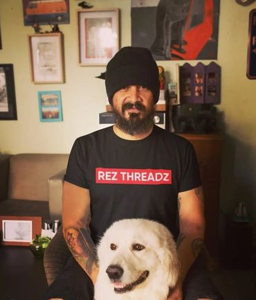 Man in black beanie and shirt with white dog in cozy room.