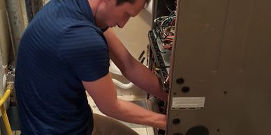 Sheldon servicing furnace in a home