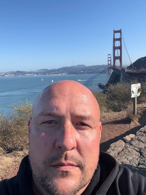 Man taking a selfie near the Golden Gate Bridge on a clear day.