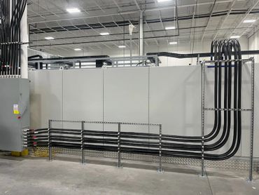Neatly organized black cables running along a wall in an industrial setting.