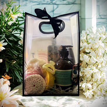 Transparent gift bag with peppermint hand soap and bath items, decorated with black ribbon.
