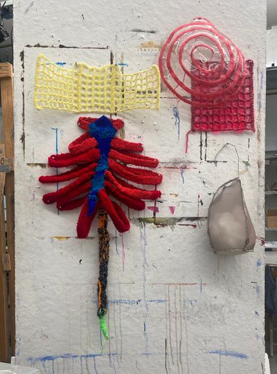 Colorful crochet wall art on a textured surface.
