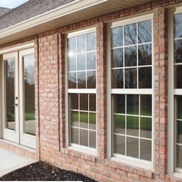 Close-up of brick exterior with modern double-hung windows and glass door.