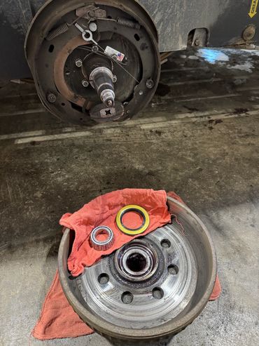 Disassembled vehicle drum brake with bearings on a red cloth.