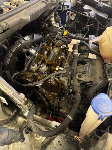Close-up of a car engine with exposed camshafts and timing chain during repair.