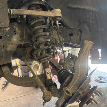 Close-up of a vehicle's suspension system with visible coil spring and control arms.