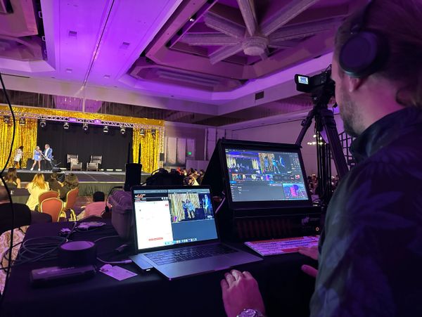 Technician live-streaming a panel discussion at an event venue.