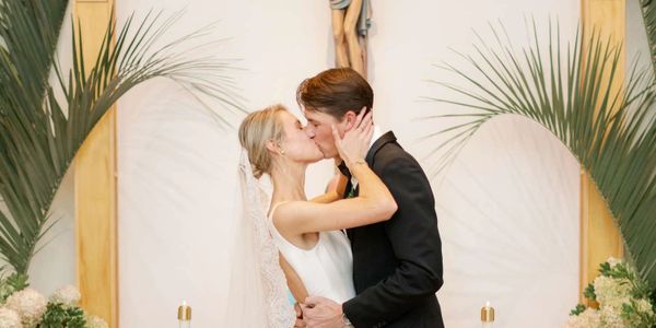 Bride and groom share a kiss during their wedding ceremony in a church.