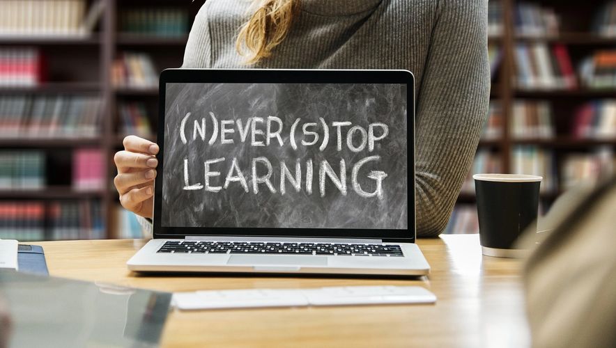 Online English student engaging with 'Never Stop Learning' on laptop in a study setting.