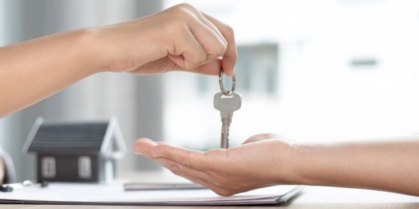 Entrega de llave de casa entre dos personas.