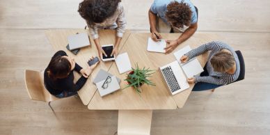 Three people working together at a hexagonal table.