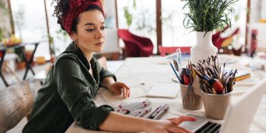 Woman working on a laptop at a creative workspace.