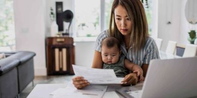 Woman multitasking with baby and bills.