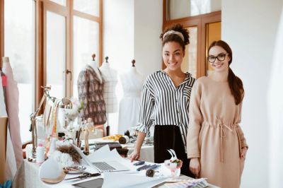 Two women smiling in a fashion design studio.