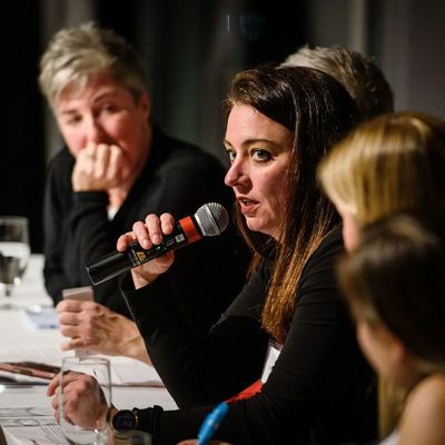 Woman speaking into a microphone at a panel discussion.