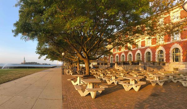 Ellis Island Café restaurant outdoor patio with the Statue of Liberty in the background.