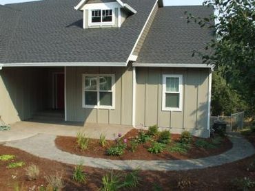 A cozy house entrance with a curved concrete pathway and landscaped garden.