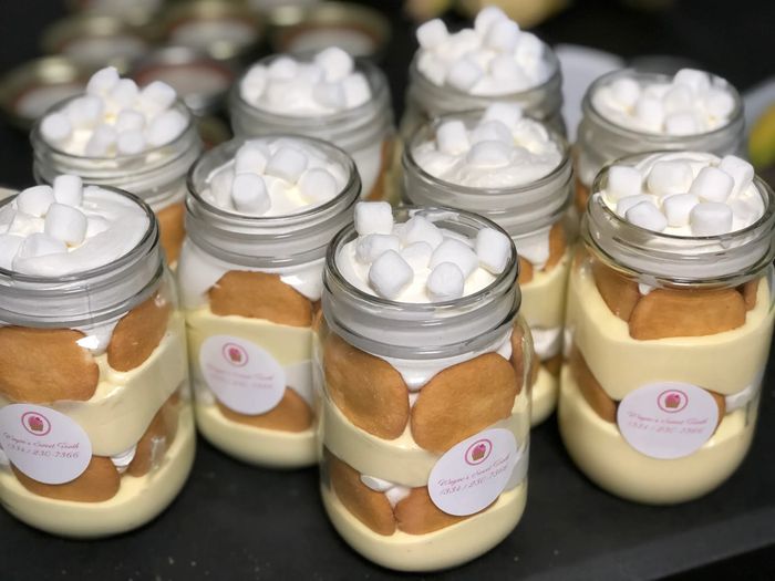 Jars filled with creamy dessert, cookies, and marshmallows on top.