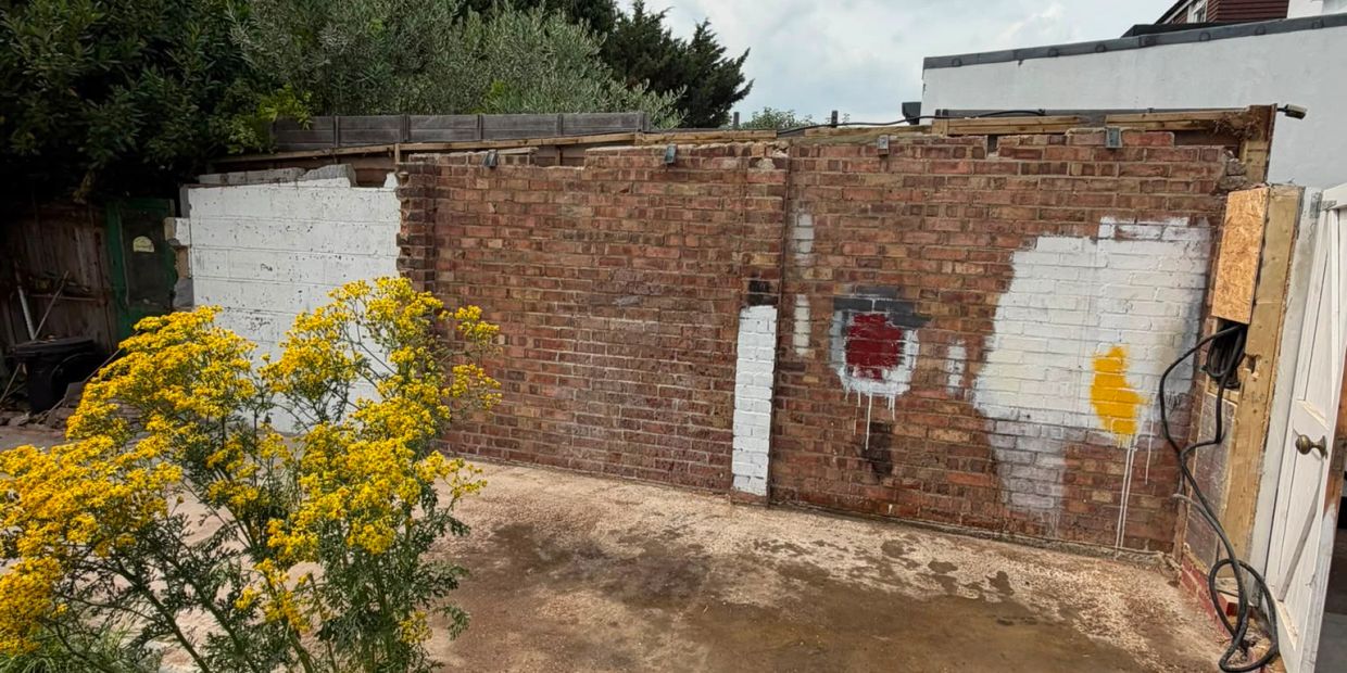 Brick wall with graffiti and yellow flowers.