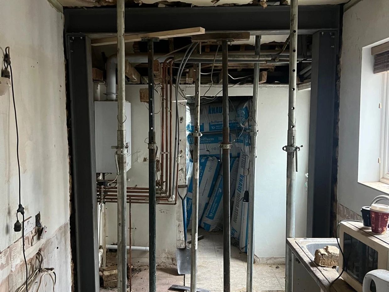 Room under construction with metal support poles.