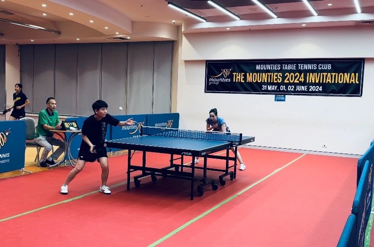 Two players competing in a table tennis match at a tournament.