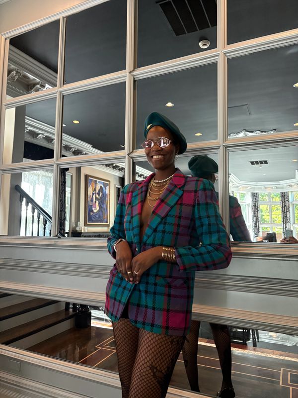 Person in colorful plaid blazer and green beret posing indoors.