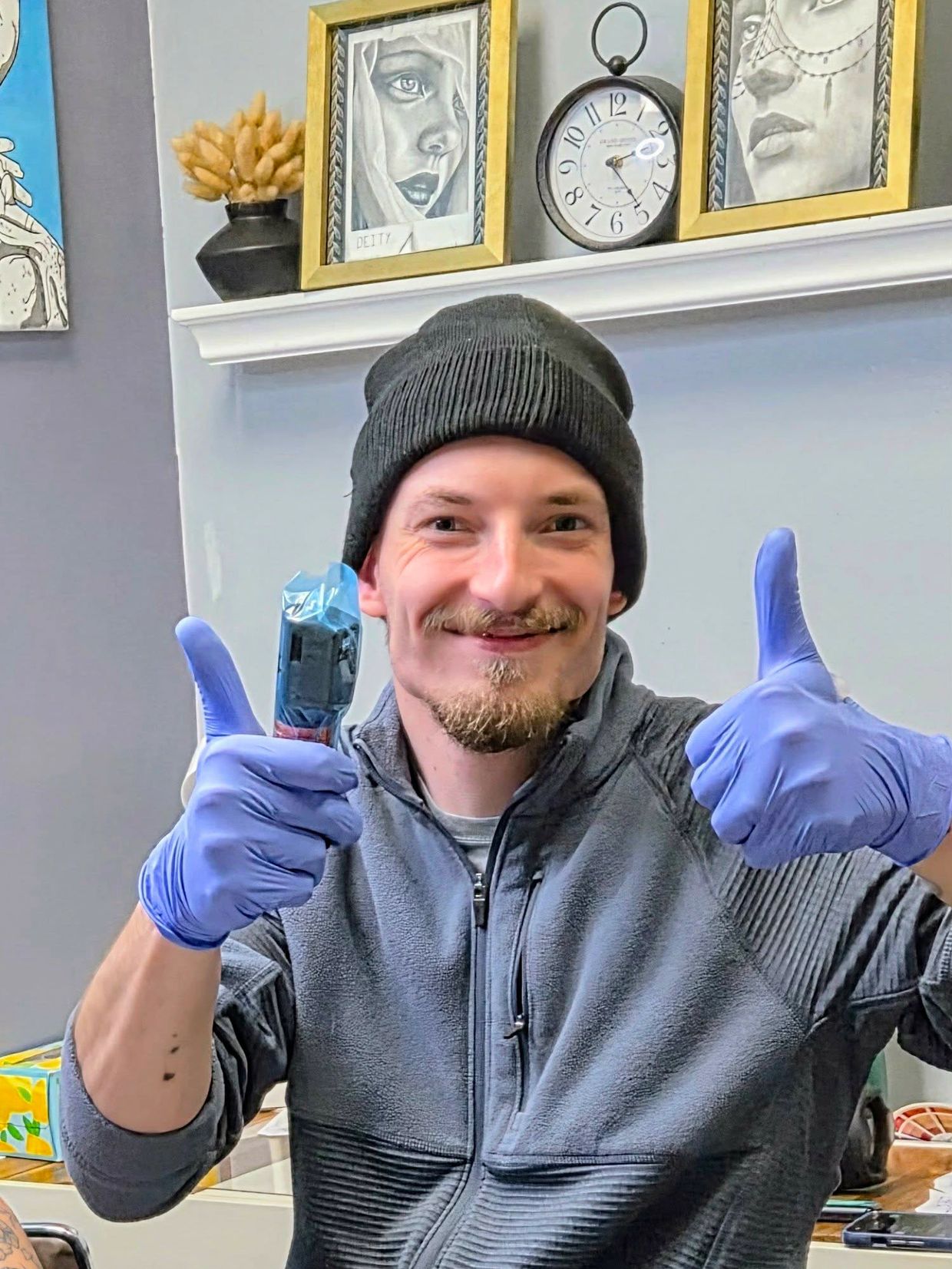 Man smiling with thumbs up wearing purple gloves and a black beanie.