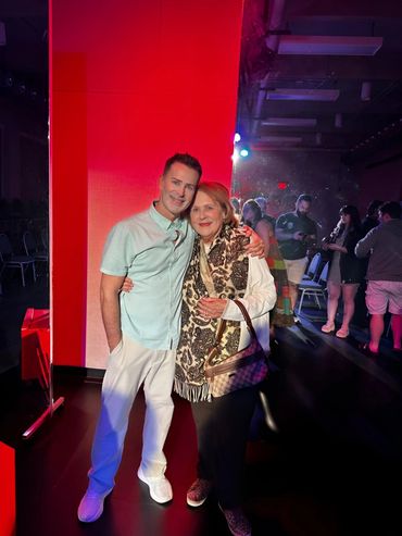 A man and woman smiling and embracing in a vibrant, colorful indoor setting.