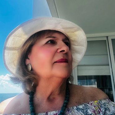 Woman in a white hat looking contemplative outdoors.