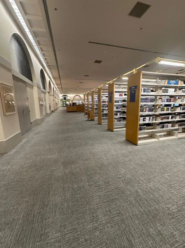 Wide aisle in a library with shelves of DVDs on the right side.