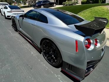 A line of sleek sports cars parked on a suburban street under clear blue skies.