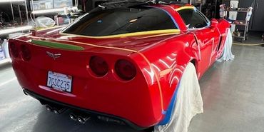 Red sports car in a garage with wheels covered by cloths.